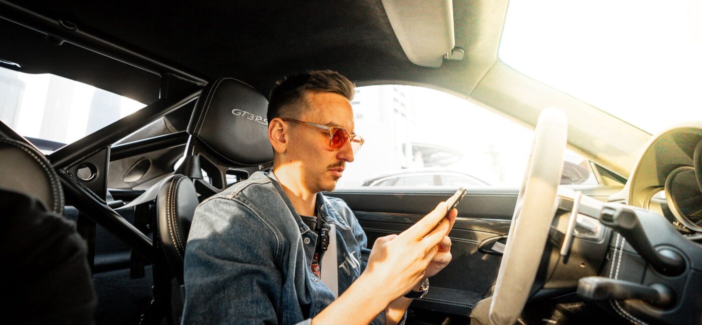 Carl Moon, crypto investor and racing driver, sitting in a sports car checking his phone