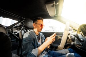 Carl Moon, crypto investor and racing driver, sitting in a sports car checking his phone