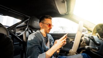 Carl Moon, crypto investor and racing driver, sitting in a sports car checking his phone