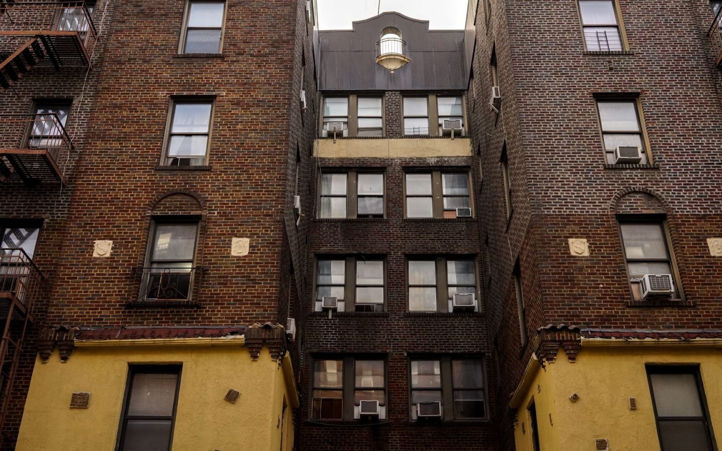 Low-angle view of brick apartment buildings with fire escapes